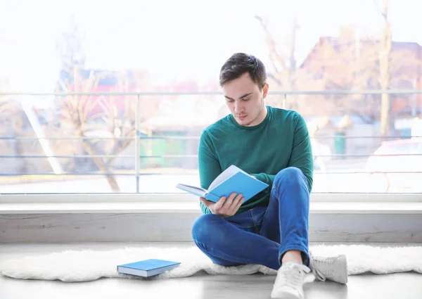 Glad ung man sitter på golvet och läsa bok — Stockfoto