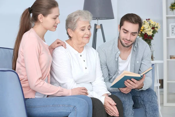 Abuela con nietos leyendo libro en sofá — Foto de Stock