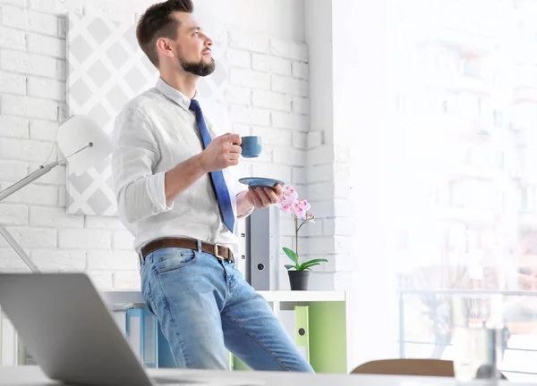 Egy fiatalember kávét iszik az irodában. — Stock Fotó