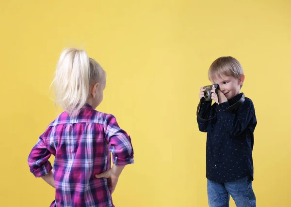 Cute kids with film camera on yellow background — Stock Photo, Image