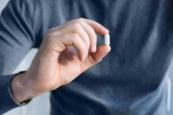 Hand of young man with pill — Stock Photo, Image