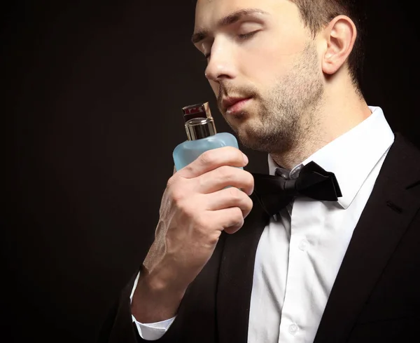 Bello giovane uomo utilizzando profumo — Foto Stock