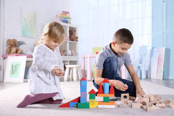 Linda hermanita y hermano jugando con bloques de juguetes en casa — Foto de Stock