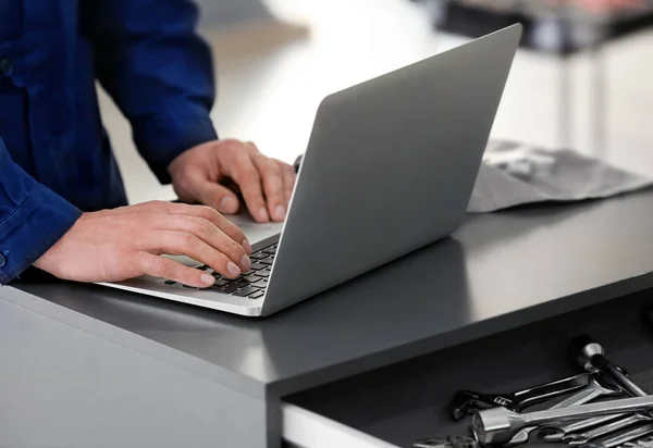 Auto mechanic working with laptop