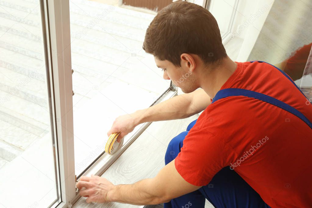 worker applying rubber strip onto window