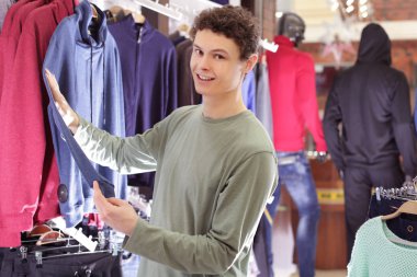 Modern dükkanda giysiler seçmek yakışıklı genç
