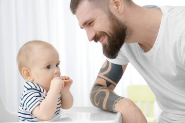 Besleme şirin küçük bebek evde yakışıklı dövmeli genç adam
