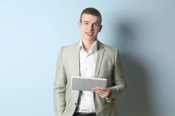 Young handsome man with tablet on light background — Stock Photo, Image
