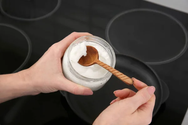 Putting coconut oil into frying pan — Stock Photo, Image