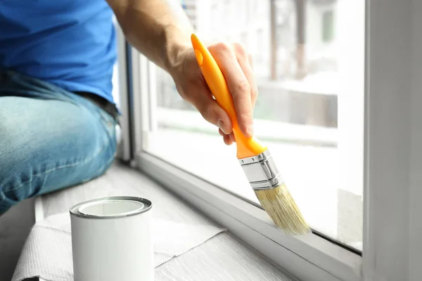 Young man painting window at home — Stock Photo, Image
