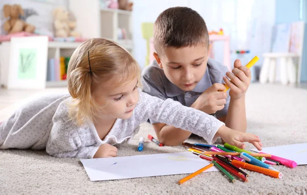 Twee schattige kleine kinderen liggend op de vloer en schilderen — Stockfoto