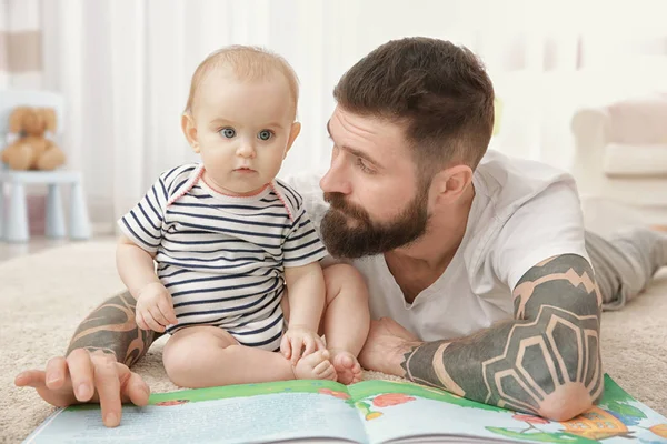 Handsome tattooed young man playing with cute little baby at home — Stock Photo, Image