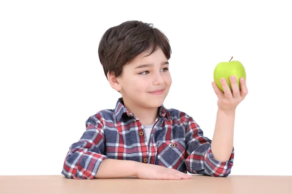 Cute little boy with apple sitting at table, on white background — Stock Photo, Image