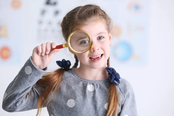 Cute little girl with magnifier on blurred background — Stock Photo, Image