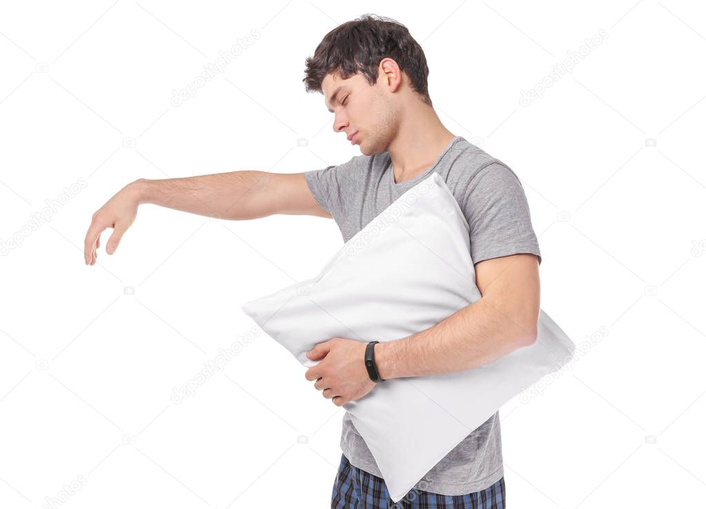 Young sleepy man with pillow suffering from somnambulism on white background