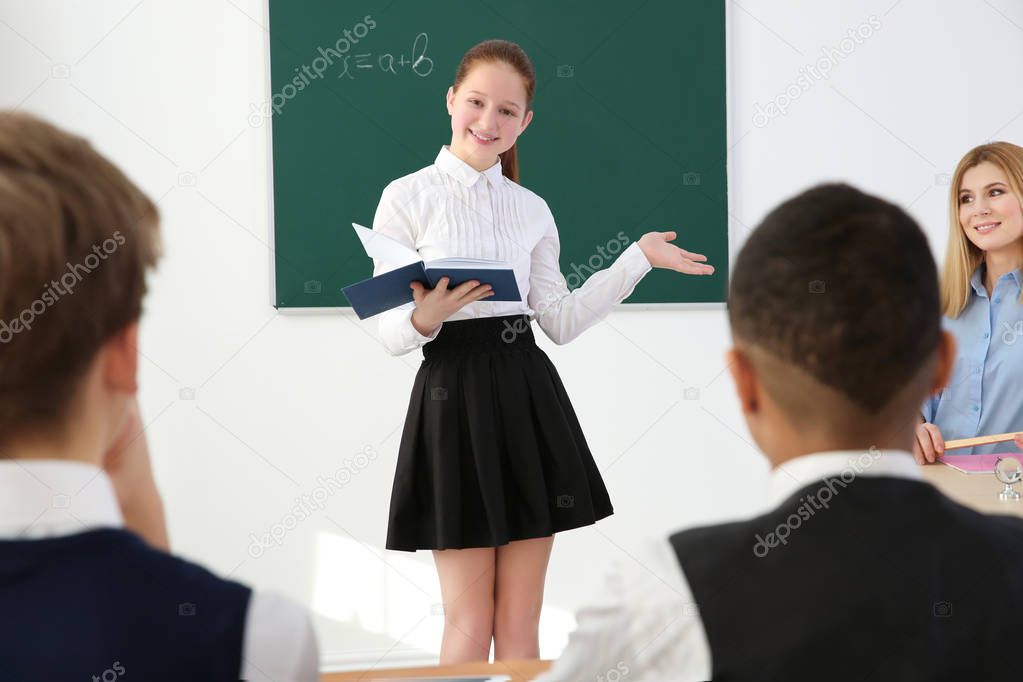 Schoolgirl answering at blackboard in classroom