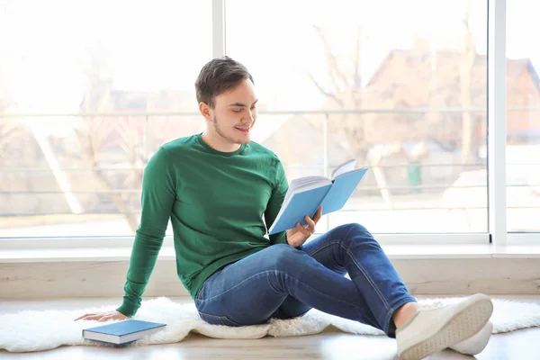 Glad ung man sitter på golvet och läsa bok — Stockfoto