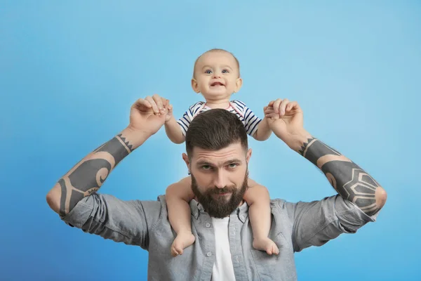 Tatuerade ungersven holding söt liten baby på ljus bakgrund — Stockfoto