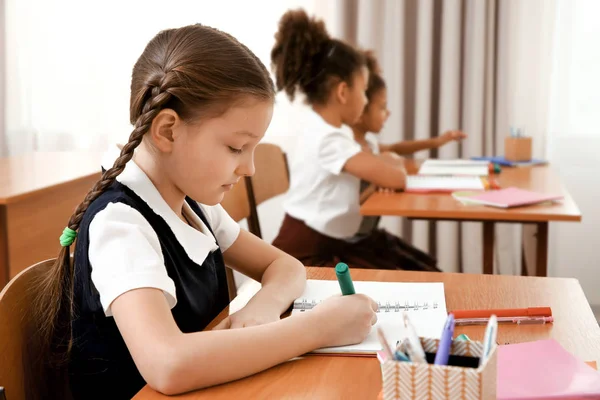 Beautiful elementary schoolgirl studying in classroom — Stock Photo, Image