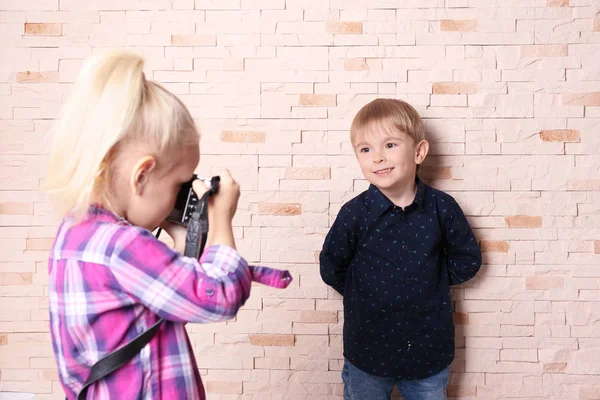 Cute kids with film camera on brick wall background — Stock Photo, Image