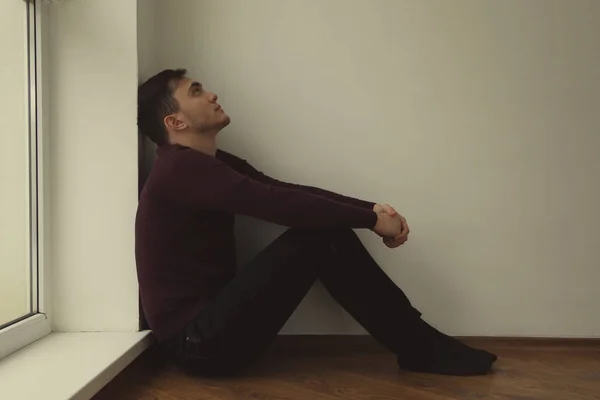 Hombre apuesto deprimido sentado en el suelo en casa — Foto de Stock
