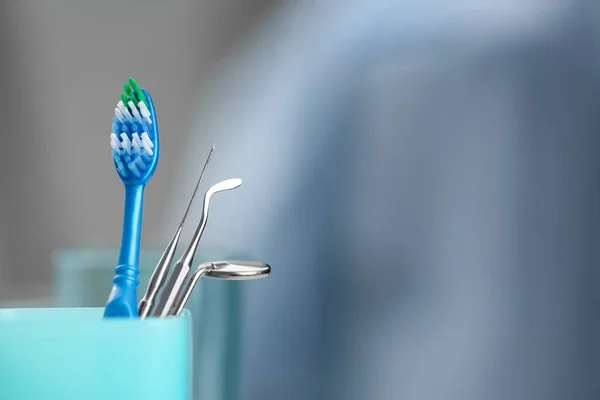 Cup with toothbrush and dental instruments — Stock Photo, Image