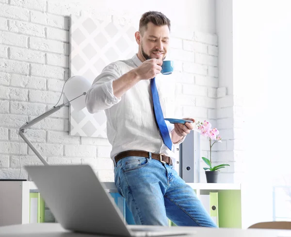 Молодий чоловік п'є каву в офісі — стокове фото