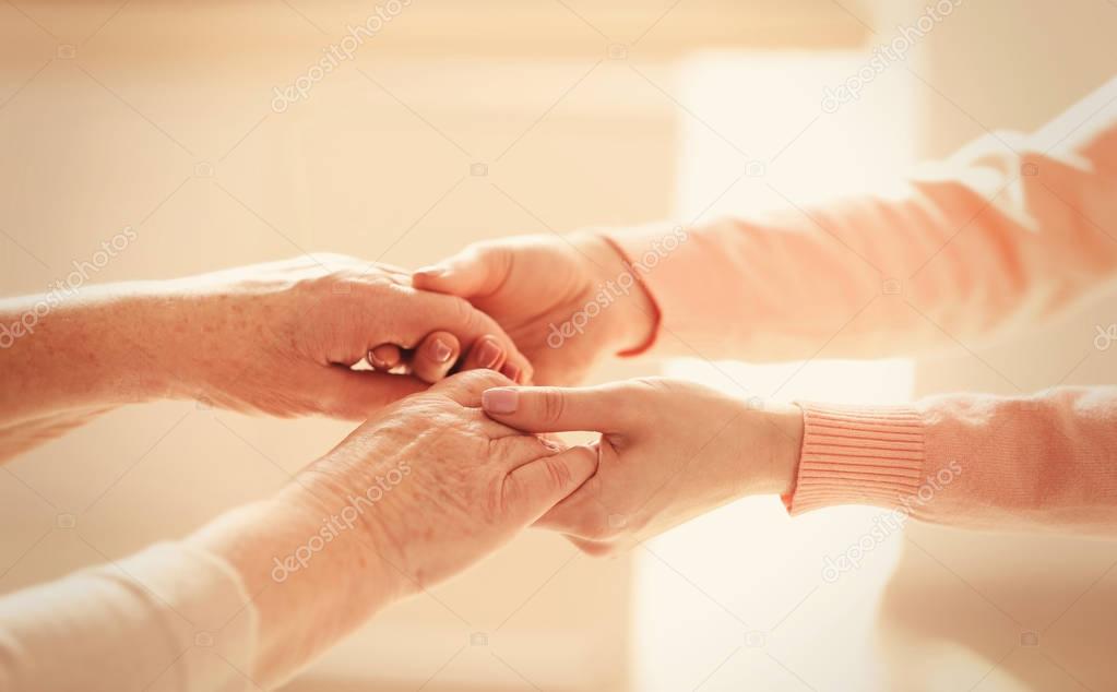 Old and young women holding hands 