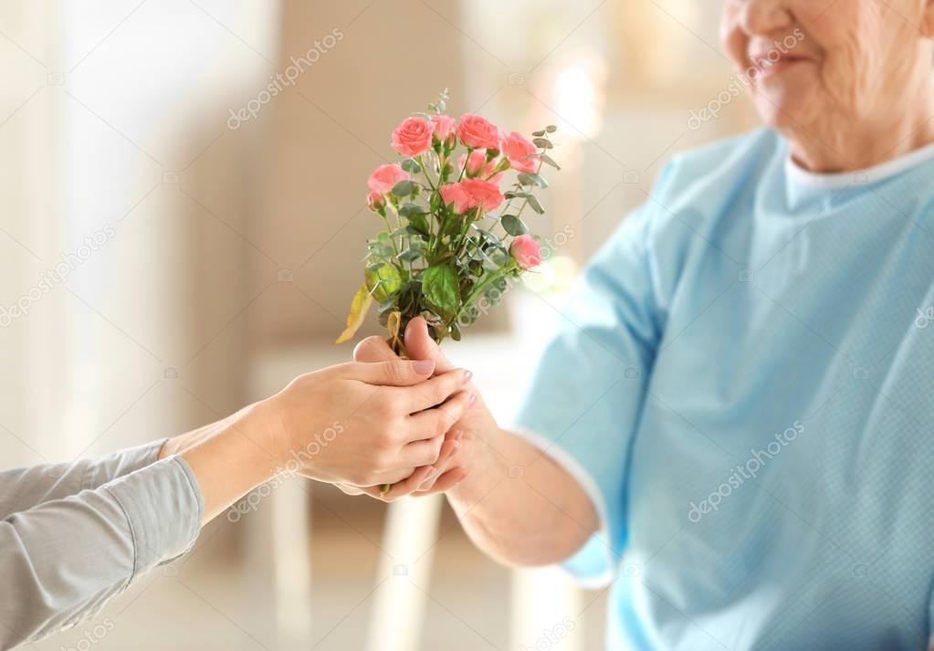 giving flowers to old woman