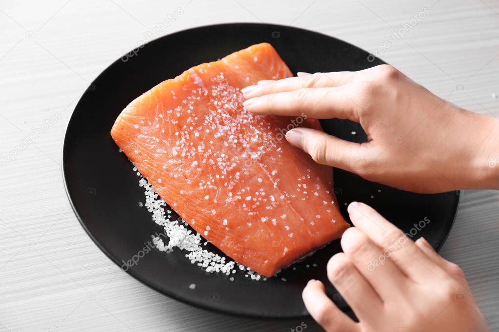 Female hands rubbing salmon fillet