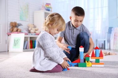 Sevimli küçük kız ve erkek kardeş evde oyuncak bloklarla oynama