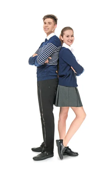 Cheerfully smiling school boy and girl standing back to back on light background — Stock Photo, Image