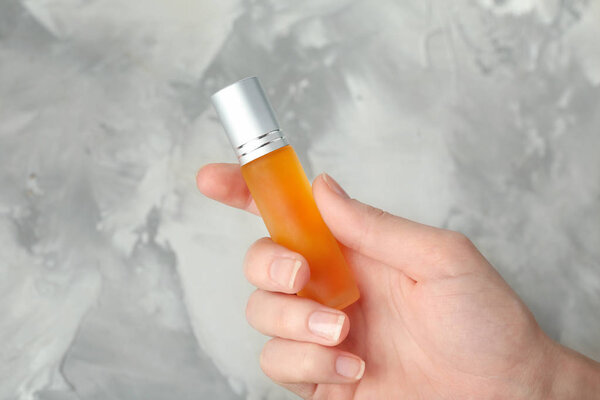 Женщина держит бутылку с духами.
 