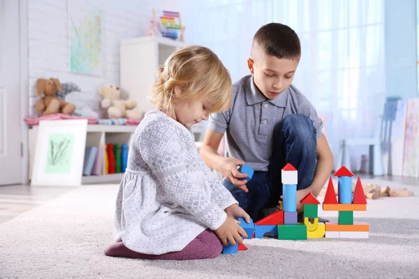 Linda hermanita y hermano jugando con bloques de juguetes en casa — Foto de Stock