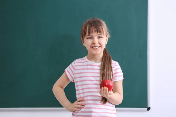Счастливая школьница сидит с яблоком — стоковое фото
