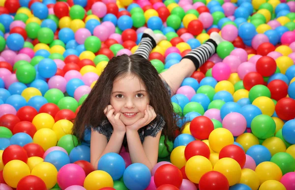 Schattig meisje speelt met plastic ballen — Stockfoto