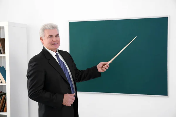 Professor sênior com ponteiro em pé perto de quadro negro — Fotografia de Stock