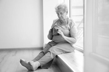 Pencere pervazına boş çantalı oturan kadın kıdemli. Yoksulluk kavramı