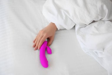 Woman holding dildo in bed
