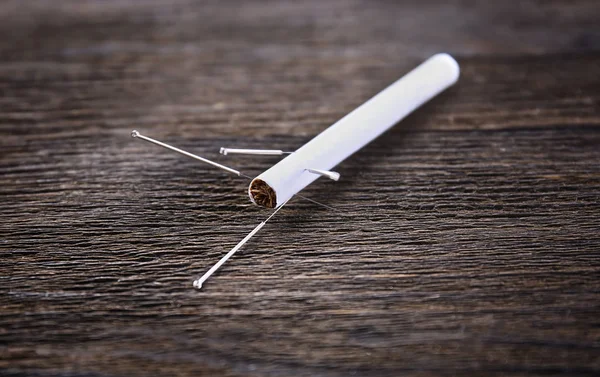 Aiguilles d'acupuncture avec cigarette sur fond en bois — Photo