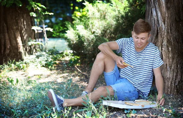 Bello ragazzo mangiare pizza su erba — Foto Stock