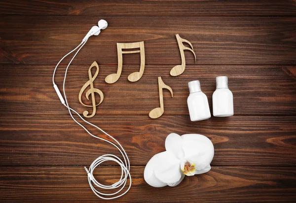 Notes with earphones and orchid with cream bottles — Stock Photo, Image