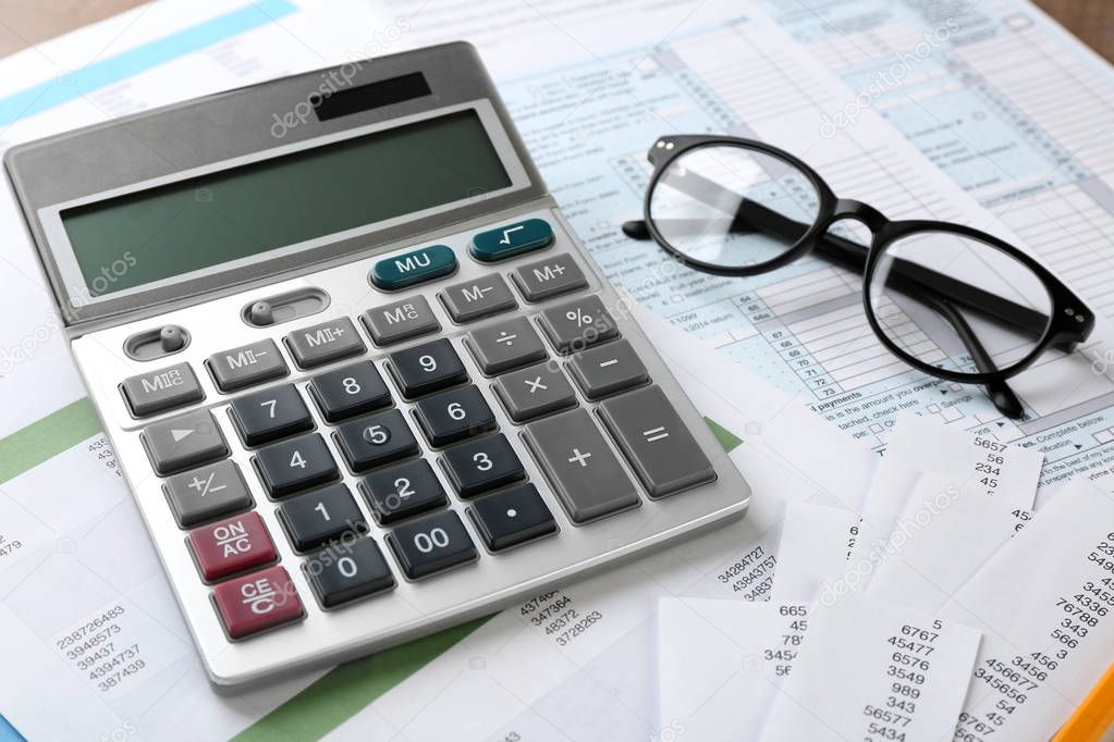 Calculator with documents and glasses on table. Tax concept