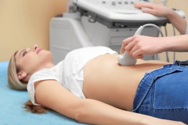 Modern klinikte ultrason taraması yaptıran genç bir kadın.