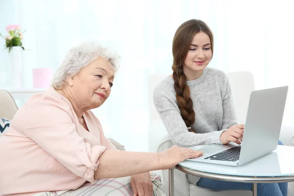 Krásná dívka s babičkou doma pomocí přenosného počítače — Stock fotografie