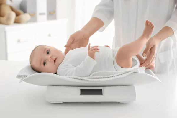 Female doctor weighting cute baby in clinic — Stock Photo, Image