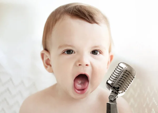 Söt baby med mikrofon på ljus bakgrund — Stockfoto