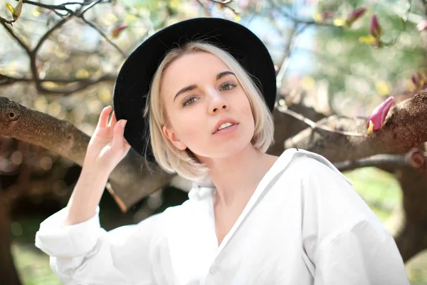 Mujer joven con sombrero cerca de magnolia árbol —  Fotos de Stock