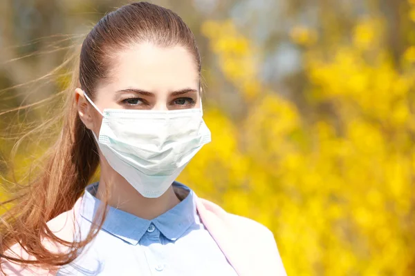 Young girl wearing face mask among blooming trees in park — Stock Photo, Image
