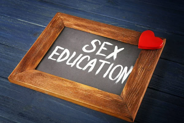 กระดานดําขนาดเล็กที่มีข้อความ EDUCATION เซ็กส์บนโต๊ะไม้ — ภาพถ่ายสต็อก
